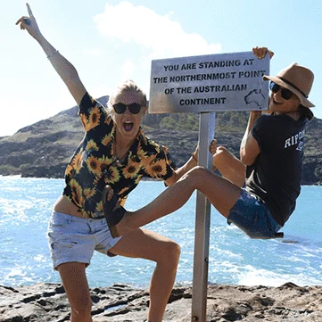 Two people at a sign reading you are standing at the northernmost point of the Australian continent